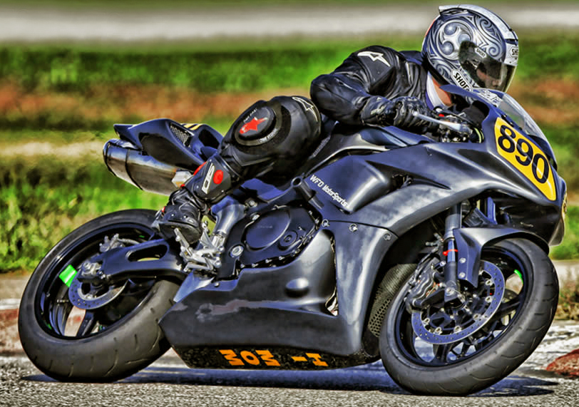 Darrell White leaned into a corner on a black sport motorcycle, number 890, on a racetrack